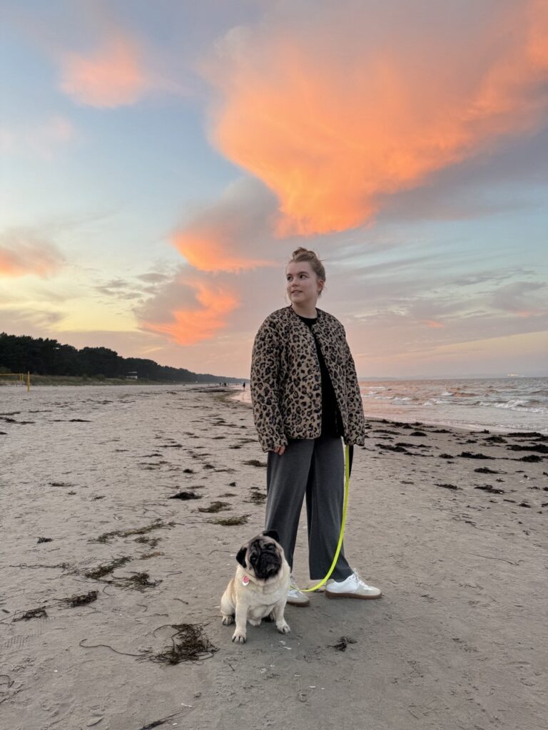 Natalie Karakina walking her pug on a beach at sunset, reflecting balance between personal life and professional role at AVOW in field marketing.